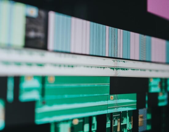 A designer using AI-powered image editing software to enhance photos with automated retouching, color correction, and background removal